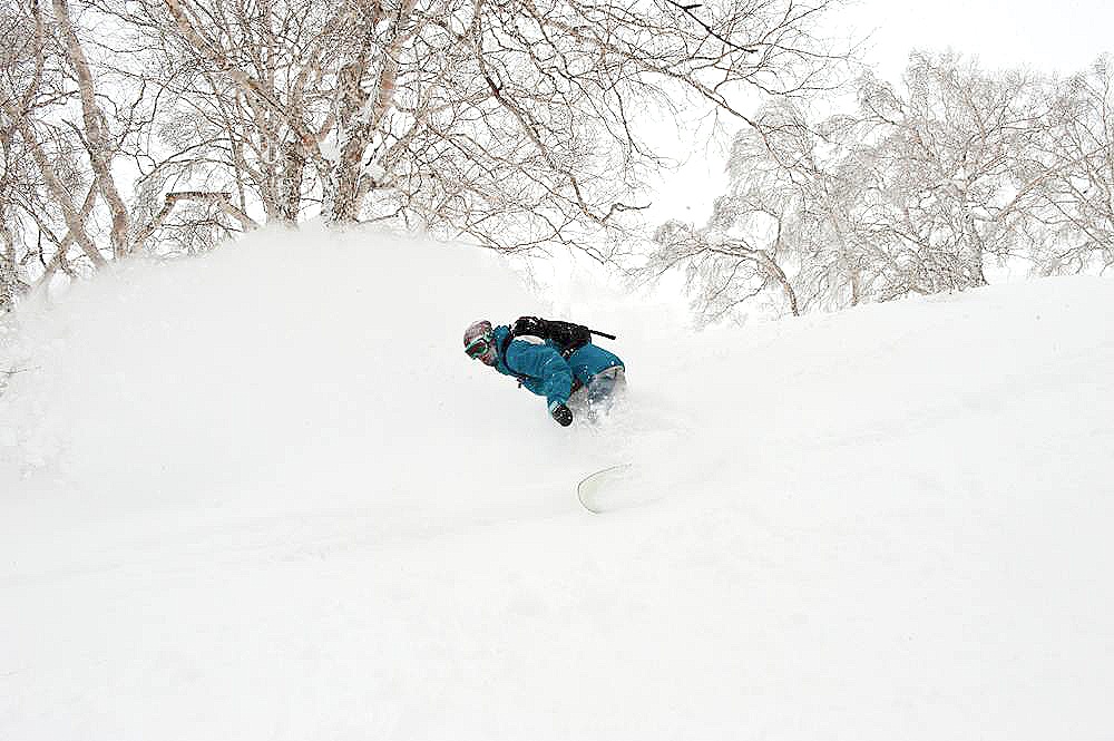 Snowboarder charging through the pow on a powder board