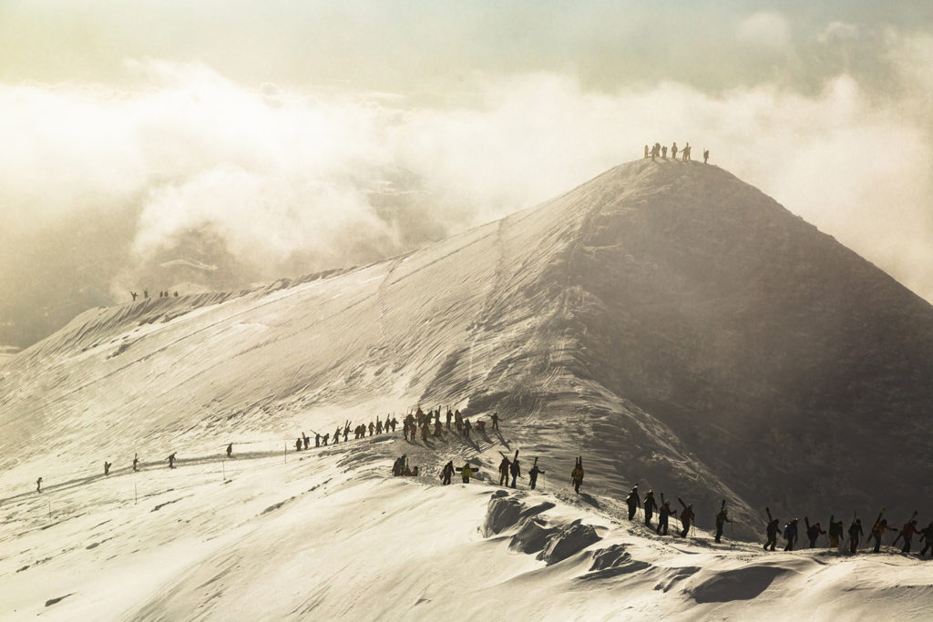 Skiers and snowboarders hike Annupuri mountain summit