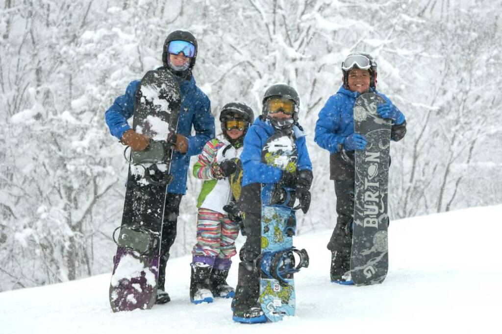 Young kids with snowboards and their instructor in Niseko