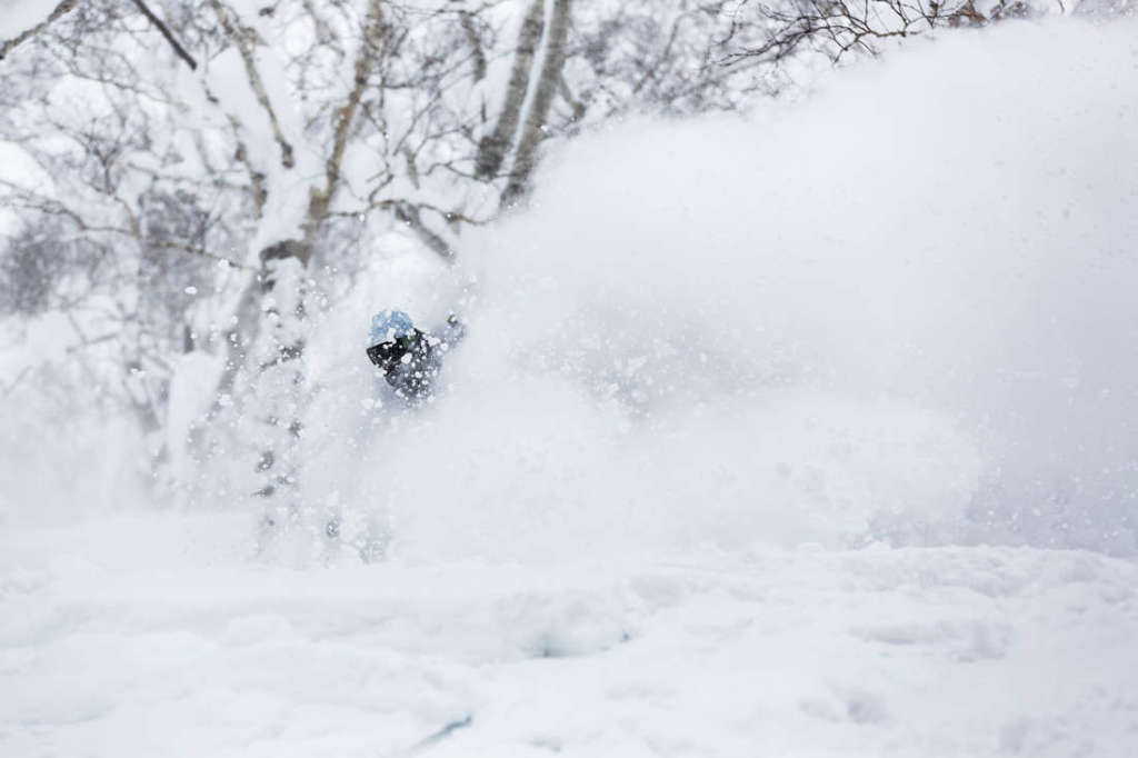 Snowboarder riding in deep Niseko powder