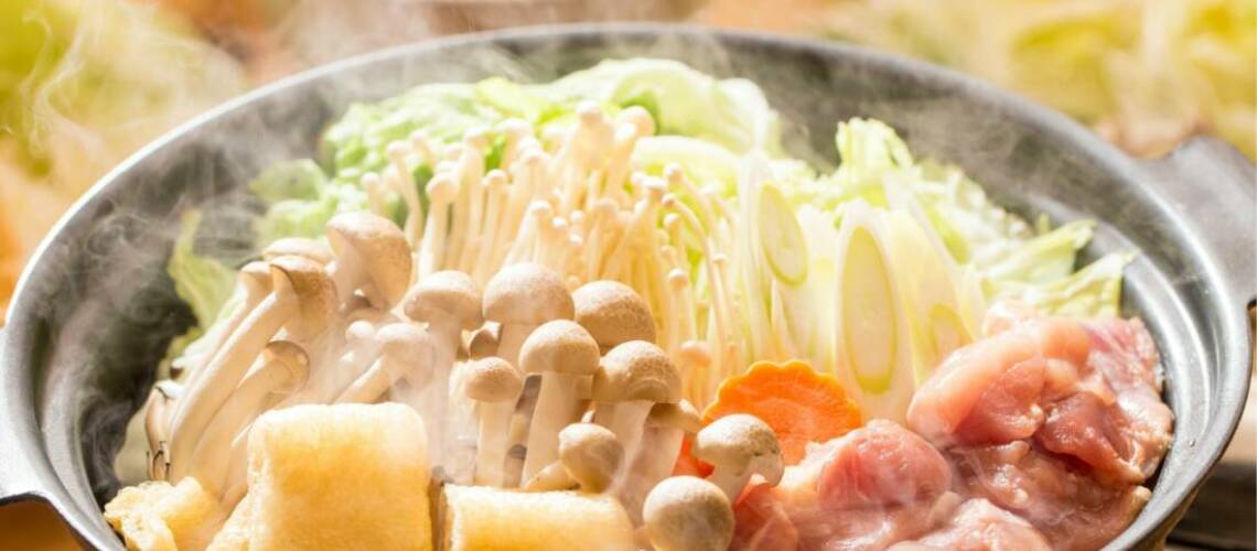 Japanese nabe hotpot with ingredients including mushrooms, meat and carrot