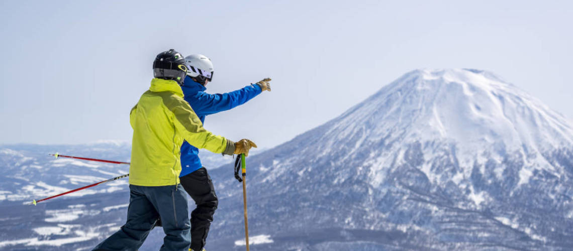 Skiers pointing to Mount Yotei